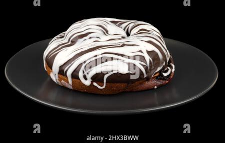 bun covered with chocolate, in a dark plate on a black background Stock Photo