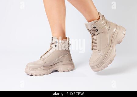 Female legs in beige leather shoes from the new collection on a white background female legs in fashionable shoes made of eco-leather spring 2022. Stock Photo