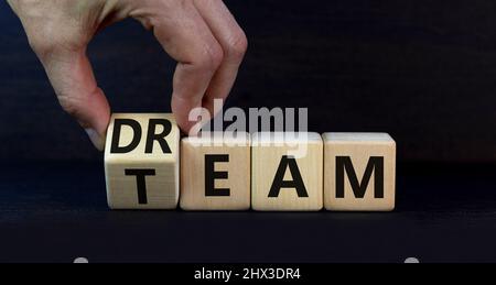 Dream team dreamteam symbol. Businessman turns wooden cubes and changes the word Dream to Team. Beautiful grey table grey background. Business and dre Stock Photo