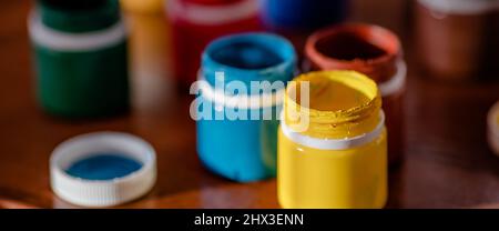Jars of colorful paint for drawing are on desk. Bright gouache or watercolor paint. Background. Stock Photo
