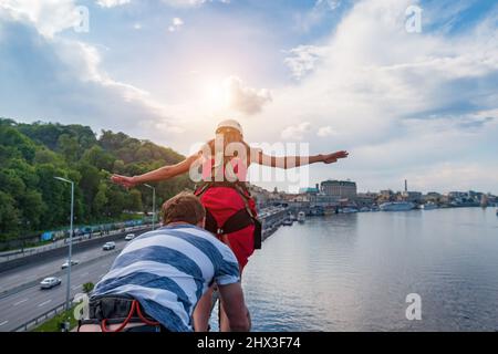 Ropjumping - jumping from the bridge on an elastic band to the river. The girl in the red dress jumps from the bridge into the water. Stock Photo