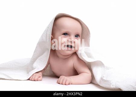 charming baby on a white background under a towel looking at the camera with a smile Stock Photo