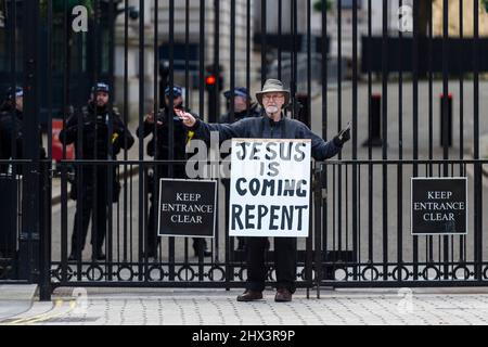 London, UK.  9 March 2022.  A man carrying a religious sign bearing the text “Jesus is coming repent” stands outside the gates of Downing Street trying to attract the attention of people passing by.  This year, Easter is on 17 April.  Easter is the most important festival in the Christian calendar. It celebrates Jesus rising from the dead, three days after he was executed.  Credit: Stephen Chung / Alamy Live News Stock Photo