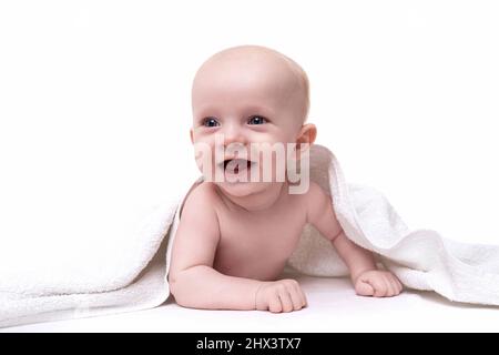 a newborn baby with a smile on his face peeks out from under a towel on a white background Stock Photo