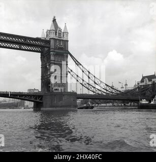 1950s, historical, Tower Bridge, City of London, London, England, UK. View of the bascule bridge and one of the two neo-gothic towers as seen from the south side of the river Thames, with the Tower of London in the background. A Horace Jones design with alternations by engineer John Wolfe Barry, the bridge over the river Thames opened in 1894.