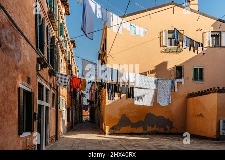 Laundry hanging out of typical Venetian facade,Italy.Narrow street with colorful buildings and clothes dry on rope,Venice.Clean clothes drying outdoor Stock Photo