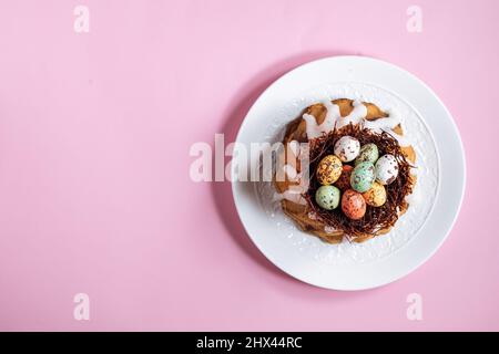 Easter cake top view on pink background. With colorful eggs placed in chocolate nest on top Stock Photo