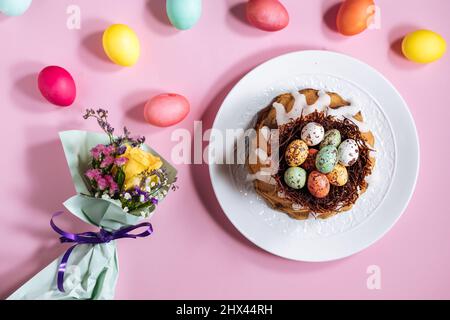 Easter cake top view on pink background. With colorful eggs placed in chocolate nest on top Stock Photo