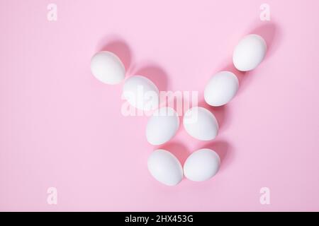 White easter eggs on pink background. Top view. Different shapes like easter bunny made from white eggs. Happy Easter simple concept Stock Photo