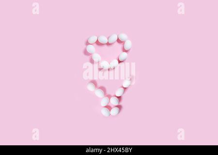 Easter bunny and heart shape made from white easter eggs on pink background. Happy easter concept. Stock Photo