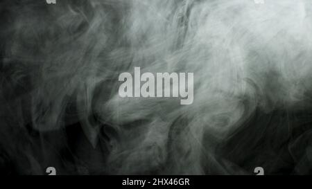 Close up for thick white smoke spreading over black background. Dense fog flying isolated in the dark. Stock Photo