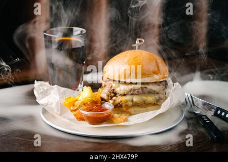 Smoked hamburger with two patties, cheese, chips, sauce and cola Stock Photo