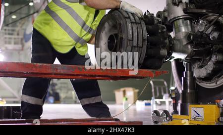 Airport worker checking chassis. Engine and chassis of the passenger airplane under heavy maintenance. Engineer checks the aircraft chassis and engine Stock Photo