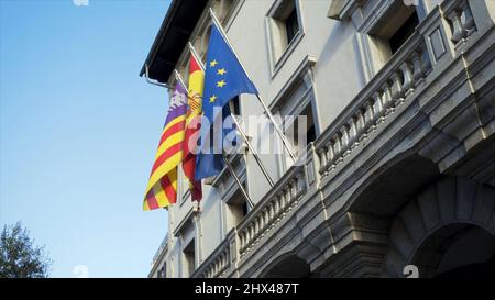 Flags of European countries on embassy house facade. Colorful banners fluttering in the wind on grey building background. Stock Photo