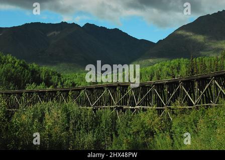 Panoramic wilderness valley forest landscape crossed by the ruin of an ancient wooden railroad trestle in Alaska. Stock Photo