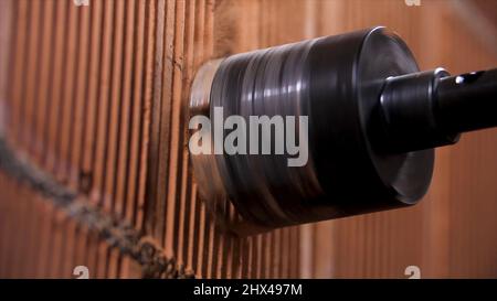 Builder worker with pneumatic hammer drill perforator making hole in red brick wall. Drilling a hole in a concrete wall for an electrical outlet. Stock Photo