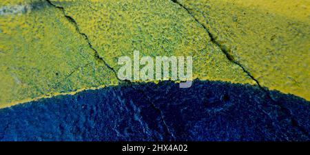 Blue and yellow painted old grungy cracked weathered concrete wall surface texture background Stock Photo