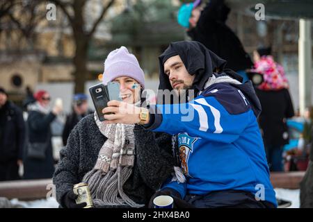 Young couple taking a selfie while celebrating Finland's Olympic gold medal in men's hockey in Helsinki, Finland Stock Photo