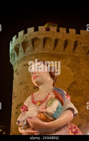 March, 2013. Valencia, Spain. View from the ground of the main ninot that represents a woman dressed as a fallera with the Torres de Quart in the back Stock Photo