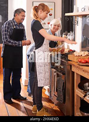 Youre never to old to learn how to cook. Shot of two senior woman watching a young woman cooking on a stove. Stock Photo