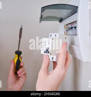 A woman changes an automatic fuse EKF in a home electrical panel. Self repair and replacement of electricity equipment in the apartment, diy - Moscow, Stock Photo