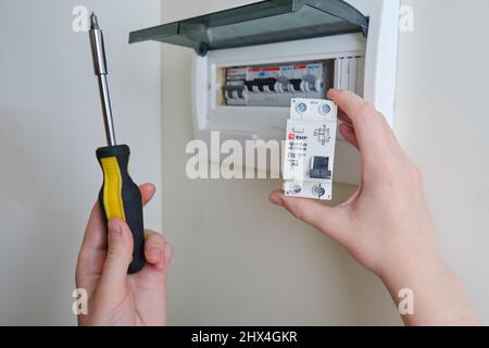 A woman changes an automatic fuse EKF in a home electrical panel. Self repair and replacement of electricity equipment in the apartment, diy - Moscow, Stock Photo
