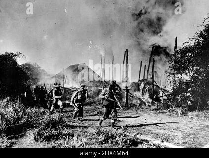 Hill Tribesmen Fighting With The British In Burma A Kachin patrol moves through the burning village of Tonnges. The village harboured Japanese police and spies. A picture taken by an army photographer accompanying a Kachin unit at Tigyaing, South of Katha, North Burma front in December 1944. The Kachin tribesmen of the North Burma hills are giving valuable assistance to the 36th. British Division with whom they are fighting their way south. April 23, 1945. (Photo by London News Agency). Stock Photo