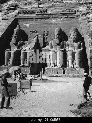 Filming An Ancient Scene -- M-G-M's 'Valley of the Kings' unit, which spent more than two months in Egypt filming scenes for the spectacular adventure story, photographs the great Abu Simbel temple, which was carved more than 4,000 years ago out of a mountain of solid rock. Robert Taylor and Eleanor Parker travelled more than 35,000 miles with the company while filming scenes for the picture. Robert Pirosh directed. The huge temple at Abu Simbel, with its colossi hewn out of rock. July 03, 1954. (Photo by Saturday Magazine). Stock Photo