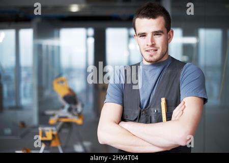 Trust him to build something solid. Handsome young contractor standing on a construction site. Stock Photo