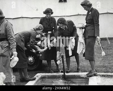 Only Women's Transport Corps In Camp - Washing up! Each camper must wash up her own 'crocks' after meals at the community sink. Members of the only women's transport corps which has continued training and recruiting without ceasing since the war are now in camp at Mychett, near Aldershot, Hampshire. They belong to the Women's Transport Service which is recognized by the Army Council as a voluntary transport organization. In times of national emergency the corps is at the service of the Government. In peace time members give valuable help to hospitals through a regular transport scheme for pati Stock Photo