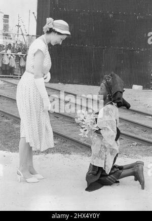 Down on her knees goes Ajibola Gibson White (11), delighted at her job of presenting orchids to the Queen at Tjora power station, Lagos, Nigeria. February 28, 1955. Stock Photo