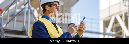 Male engineer using mobile phone outdoors at factory Stock Photo
