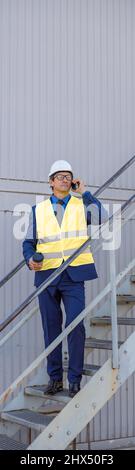 Male engineer standing on stairs and having phone conversation Stock Photo