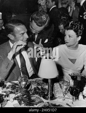 Must be some kind of sign language that Arthur Cameron, spouse of Kay Aldrich and former hubby of June Knight, is trying to get over to Randy Scott and wife, Pat Stillman. September 08, 1946. (Photo by Jay Scott). Stock Photo