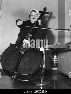 Looks As If She Really Know How - Little Elizabeth Hansi-Adam, two years old, gets into the act in a big way as she arrives in New York aboard the liner Comte Biancimano. She's really enjoying "sawing" on the bass fiddle for photographers covering the ship arrival. She was with her parents, retuning to their Manhattan home after a six-month European tour with the Julian String Quartet. December 31, 1955. (Photo by United Press Photo). Stock Photo