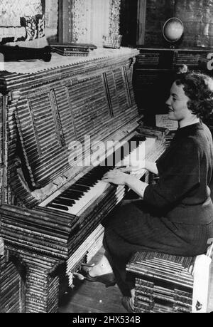 News 'Heat" - In The Paper House -- Joan Crayson, a visitor plays the newspaper piano at the Stepman house. The piano has wooden frame but the paneled veneer is made of rolled newspaper. Don't know what to do with old newspapers? why not follow  Elis and  Stenman of Pigeon Cove, Massachusetts.U.S.A - build a house!Back in 1922, they began collecting newspapers in a big way. Three years and was complete. Working from a base of wooden floors, foundations and beans, the Stenmans completely enclosed the frame structure with newspapers. Large sheets were folded and glued to form paper bui Stock Photo