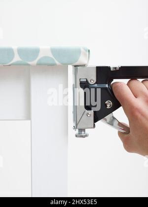 Covering a kitchen table, securing the oil cloth underneath the table top using a staple gun Stock Photo