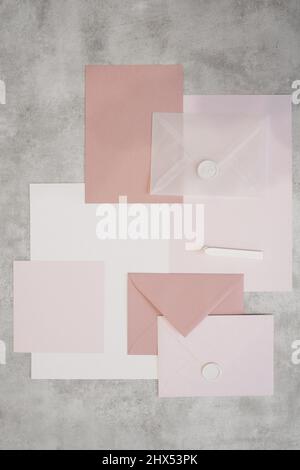 Top view of composition of colorful sheets of paper, white and pink envelopes sealed with wax, white sealing wax. Stock Photo