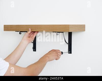 Fitting walls shelves, attaching the shelf to the wall using a screwdriver Stock Photo