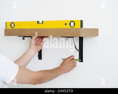 Fitting wall shelves, marking the position using a spirit level Stock Photo