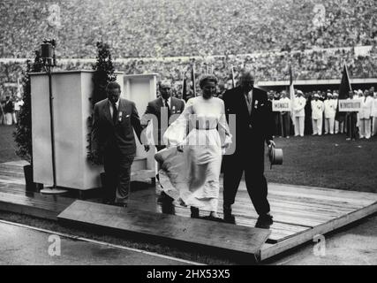 Woman in White Gives Sensational Start to Olympic - A woman, dressed in white flowing robes, is escorted from the rostrum in the stadium here during the opening ceremony of the 1952 Olympic Games. The woman, Barbara Ratraut Player, a West German student, made a mad dash round the track and ran up to the rostrum, where she seized the microphone and attempted to address the Vast crowd. She got Ladies and Gentlemen in English when she was seized by Officials and hustled away. July 20, 1952.