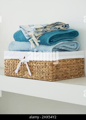 Stack of towels in basket on shelf Stock Photo