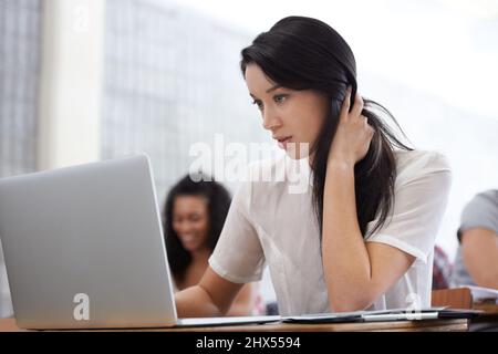 Bad grades getting you down. Shot of a bored young college student sitting at a laptop in class. Stock Photo