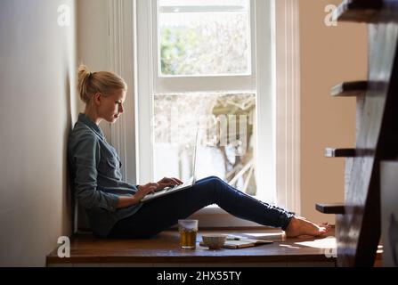 Using my laptop to work from home. A young woman using her laptop at home. Stock Photo
