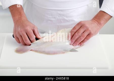 Preparing lemon sole, cutting into fillets, releasing fillet at backbone and fins Stock Photo