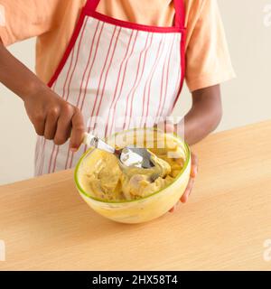 Boy using spoon to stir ingredients in glass mixing bowl, close-up Stock Photo