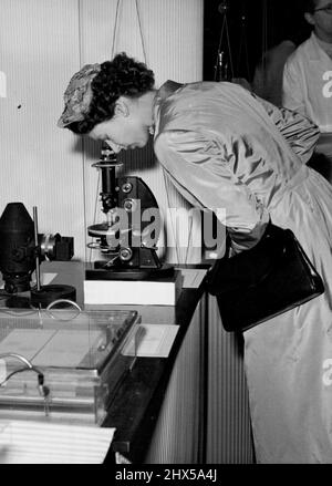 The Queen Visits Hammersmith Hospital Closing one eye, H.M. The Queen looks intently through a microscope in one of the laboratories during her visit to the Hammersmith Hospital this afternoon. H.M. The Queen this afternoon paid a visit to the Hammersmith Hospital, which is celebrating the 50th. Anniversary of it's foundation, in conjunction with the inauguration of the Postgraduate Medical School of London University which is housed at the Hospital. June 06, 1955. (Photo by P.N.A. Rota) Stock Photo