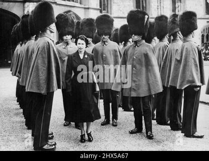 Queen's Farewell Inspection of Grenadiers - The Queen, dressed in black, inspects grey-caped Grenadier Guardsmen at Windsor Castle to-day (Monday) - her 26th birthday. This was the first ceremonial parade of the Queen's reign and it was also a farewell. She was saying good-bye to the Grenadiers as Colonel of the Regiment. As Sovereign, she is new Colonel - in - Chief of all Guards regiments. Six hundred officers and men were on parade. To-day's parade was held on the tenth anniversary of the first inspection by the Queen - then Princess Elizabeth - as colonel of the Grenadiers. April 21, 1952. Stock Photo