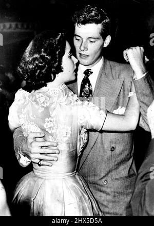 Hollywood Newly-Weds -- Keeping in step are film actress Elizabeth Taylor and her husband Conrad Hilton, Junior, ***** their 'second honeymoon' by a visit ***** flower petals in relief. Her husband's gay tie caught the eye of dancers. June 5, 1950. (Photo by Paul Popper Ltd.). Stock Photo