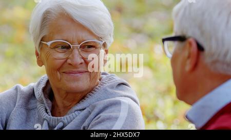 Retired woman in her 70s smiling, and talking to her husband. Outdoor close up shot. High quality photo Stock Photo